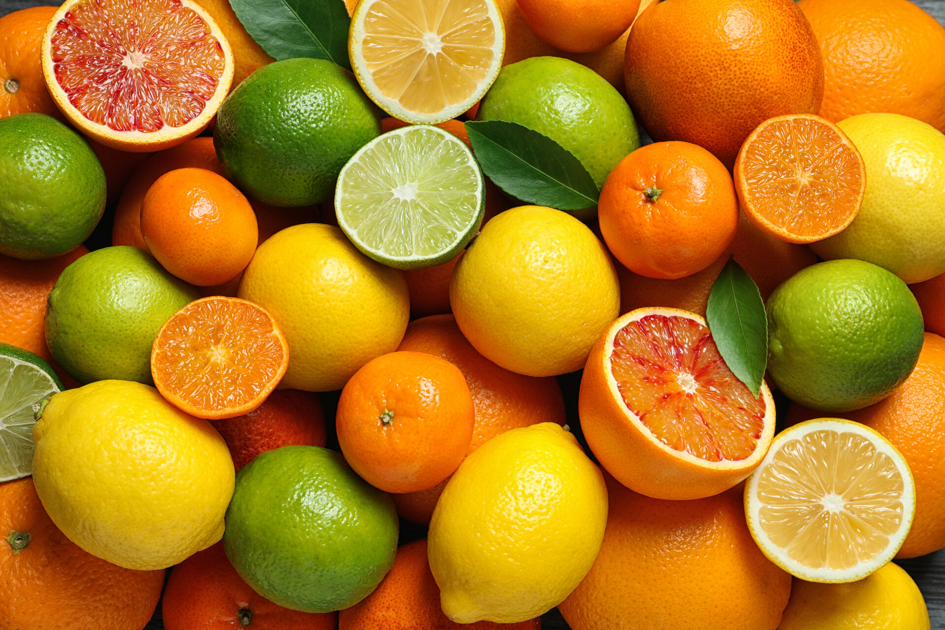 Many different citrus fruits all in a pile together.
